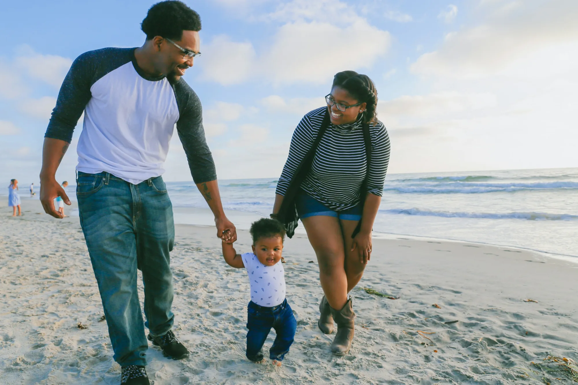 A family of three walking hand in hand along the lakeshore