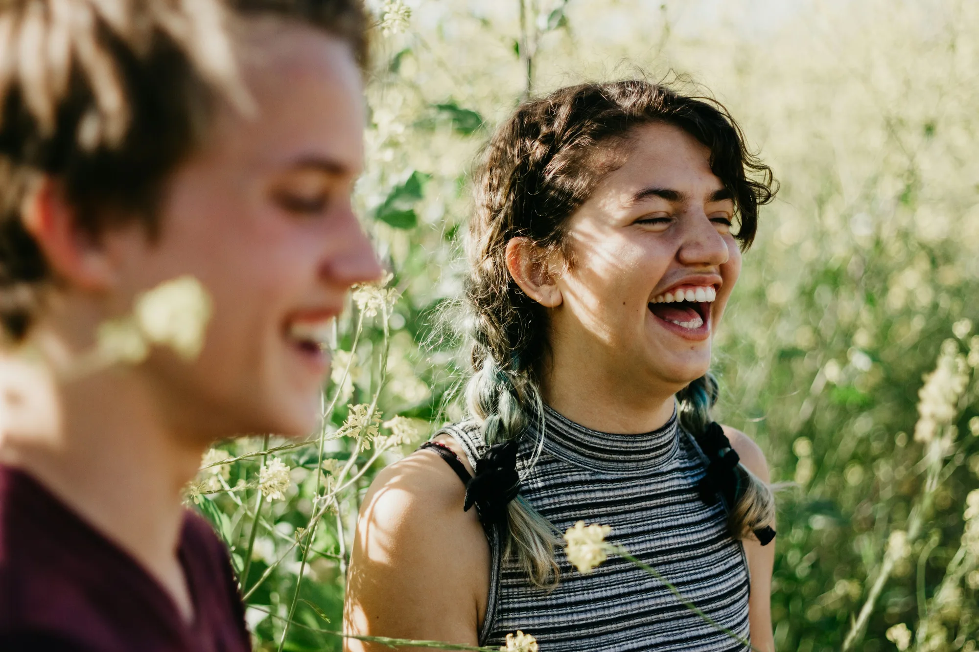Two friends laughing together in a sunlit meadow